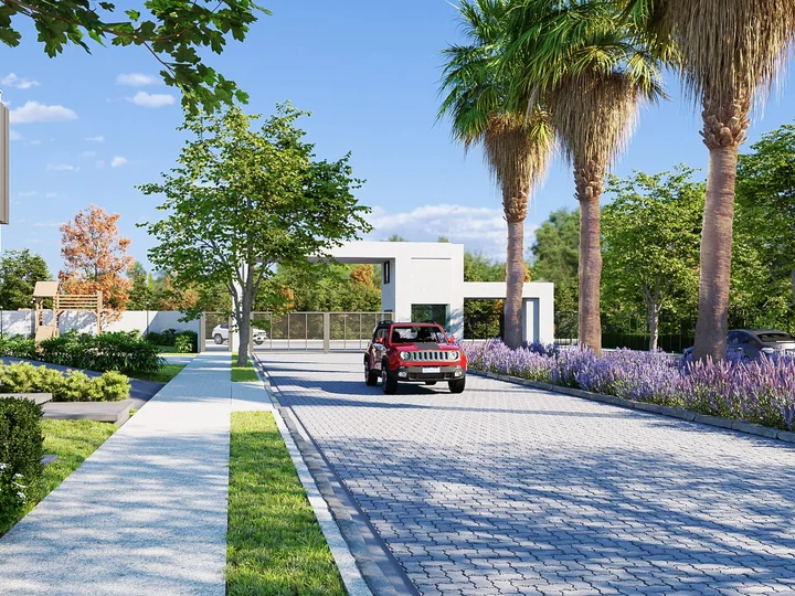Alameda arborizada do Villa Natura Boulevard, com palmeiras, jardins e veículo.